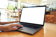 © Farknot Architect - Mockup image of a hand touching on laptop computer touchpad with blank white desktop screen on the table