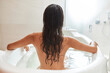 Naked young woman taking bath at home
