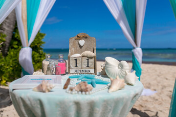 Poster - Close up view of table for the beach wedding ceremony with decoration of shells, jars with color sand, wooden calendar inside bamboo gazebo, Punta Cana, Dominican Republic