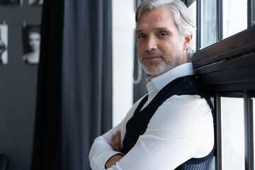 Wall Mural - Success concept. Stylish mature bearded man in elegant suit standing near the window