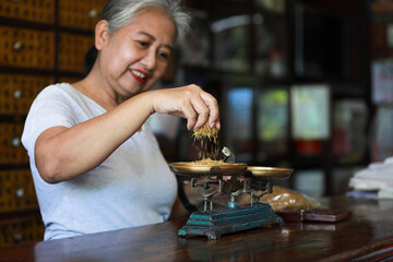 The old doctor of traditional medicine weight scales dry lotus pollen china herbs in chinese medicine shop.