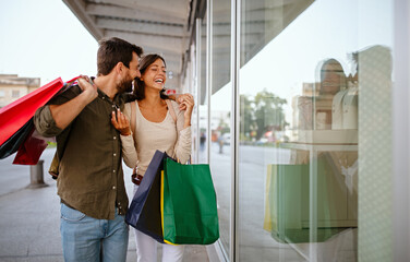 Wall Mural - young happy couple with shopping bags in the city, having fun together.