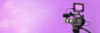 © OneClic - video camera on purple background with bokeh, movie or television broadcasting banner