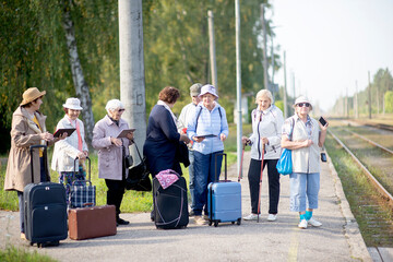 Wall Mural - A group of positive senior elderly people travelers using tablets waiting for train before going on a trip