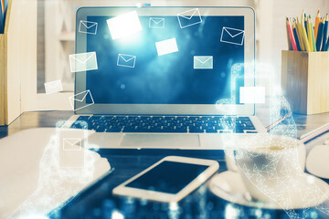 Desktop computer background in office and flying envelops hologram drawing. Double exposure. Electronic mail concept.