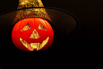 Halloween pumpkin smile and scary eyes for party night. Close up view of scary Halloween pumpkin with eyes glowing inside at black background. Selective focus