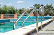 Dirty outdoor pool. Cleaner of swimming pool. Man cleaning outdoor swimming pool with vacuum tube cleaner in summer. Seasonal preparations. Cleaning systems for swimming pools.
