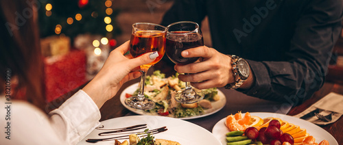 Cuadros en Lienzo hands with glasses clinking against the background of Christmas tree lights and