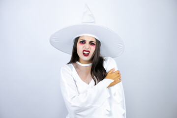 Woman wearing witch costume over isolated white background with pain on her shoulder and a painful expression