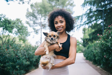 Happy ethnic woman hugging cute Chihuahua dog