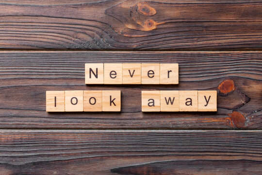 Never look away word written on wood block. Never look away text on wooden table for your desing, concept