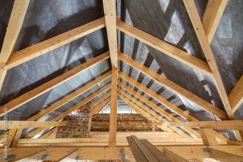 Fotografía Attic of a building under construction with wooden beams of a roof structure and brick walls