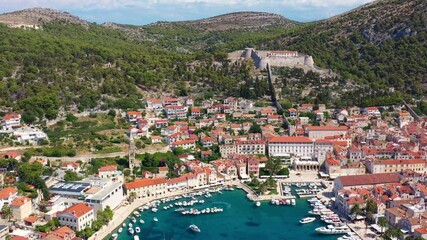 Wall Mural - Aerial footage with backward motion of the Hvar old town with its famous luxury marina by the Adriatic sea in Croatia