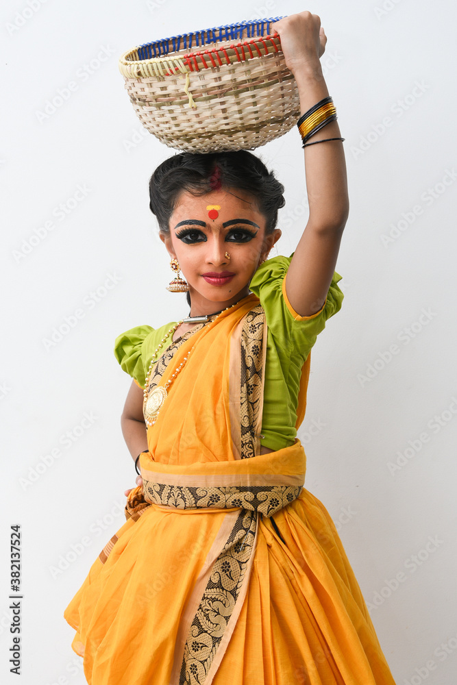 Beautiful Indian girl or women or kid wearing sari or saree as Indian folk, classical  dancer in dance pose wearing traditional dress for females in Kerala,  India. wearing ornaments and makeup. Stock-foto |