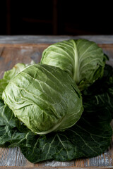 Two heads of young fresh green cabbage on rustic old wooden background, close up, top view