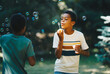 © Sanja - Cute african boy blowing bubbles outdoors with his friend and having fun on beautiful sunny day.
