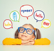 © Myst - Beautiful cute little girl with eyeglasses looking at hello word in spanish, english, russian, chinese and american sign language in speech balloons. K-12 foreign language learning concept.