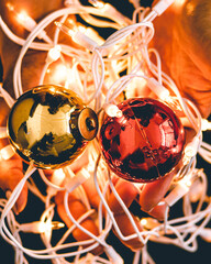 Canvas Print - Closeup shot of a person holding red and golden Christmas balls with lights