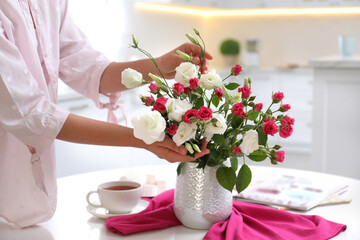 Wall Mural - Woman with bouquet of fresh flowers in stylish vase at table, closeup