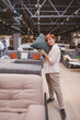 © mad_production - Vertical shot of a female customer trying soft cushion, shopping at furniture store