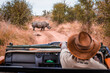 © Marek - Safari guide in jeep pointing at Rhino in the wild