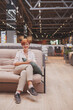 © mad_production - Vertical shot of a cheerful female customer sitting on a new couch at furniture store