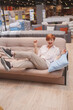 © mad_production - Vertical portrait of a female customer looking excited, having fun at furniture store