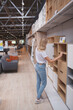 © mad_production - Vertical rear view shot of a female customer examining cupboards on sale at furniture store, copy space