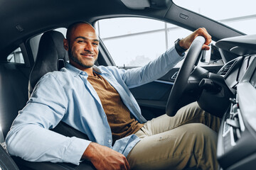 Portrait of a handsome happy African American man sitting in his newly bought car