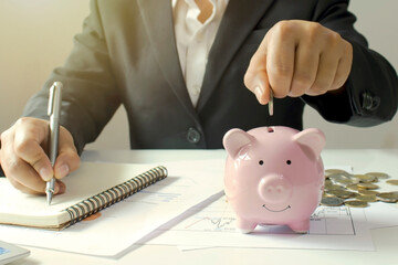 Wall Mural - Close-up of a businesswoman holding a coin in a piggy bank, a concept of saving money for financial accounting.