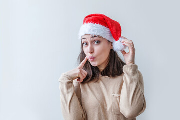 Wall Mural - Beautiful girl in red Santa Claus hat isolated on white background looking happy and excited. Young woman portrait, true emotions. Happy Christmas and New Year holidays