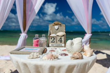 Poster - Close up view of table for the beach wedding ceremony with decoration of shells, jars with color sand, wooden calendar inside bamboo gazebo, Punta Cana, Dominican Republic