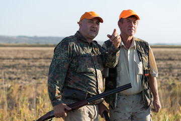 Wall Mural - Duck hunters with shotgun walking through a meadow.