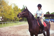 Cheerful teenage girl equestrian riding chestnut horse