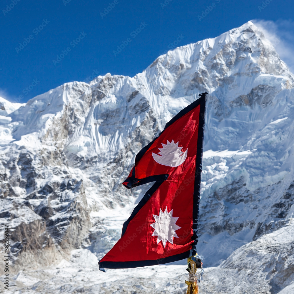 Flag of Nepal in the Himalayas with a snowy mountain