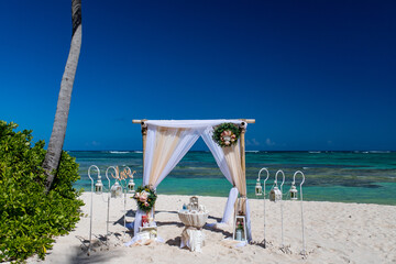 Poster - Wedding bamboo gazebo, decorated with tropical flowers and coloured fabrics on the paradise beach with palm trees, white sand and blue water of Caribbean Sea, Punta Cana, Dominican Republic