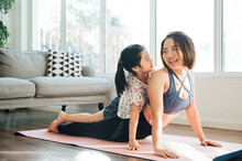 Asian Young Mom And Daughter Practicing Yoga At Home