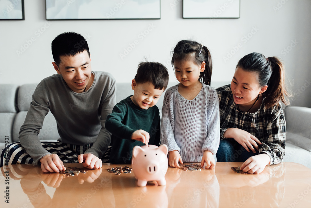 Family saving money in a piggybank Stock Photo | Adobe Stock