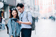 © MaaHoo Studio/Stocksy - Young asian couple traveling in a city downtown and checking information on tablet