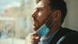 © america_stock - Sad businessman remove medical mask at home sitting on windowsill and looking at street on quarantine COVID-19 pandemic epidemic depressed portrait slow motion