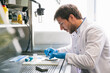 © Inuk Studio/Stocksy - Side view of man in white coat sitting at table and examining samples while working in modern lab.