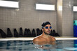 © Inuk Studio/Stocksy - Sporty fit man in swimming goggles sitting in pool.