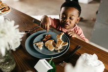 A Kid Sitting At A Table Eating Breakfast.