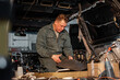 © Milles Studio/Stocksy - Male technician cutting material in vehicle trunk