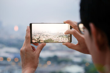 Young people take pictures of the buildings in the city. Sunrise time He uses a high-angle recording photo phone.Travel concepts and technology