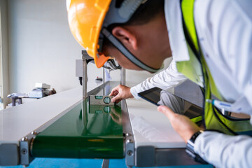 Asian man Mechanic technician worker use a water level meter working and Assemble the product sorting machine conveyer in industrial factory.