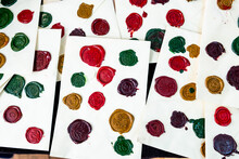 Multiple Colorful Wax Seals Stamped On White Pieces Of Paper At A Shop As Samples.
