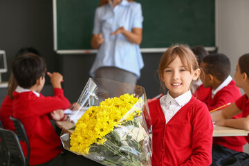 Canvas Print - Little schoolgirl with bouquet for her teacher in classroom