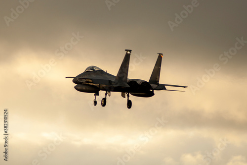 Fotografie, Obraz Avión de combate F-15 aterrizando al atardecer