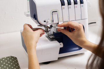 Women at work: Girl threading the needle of a sewing machine.